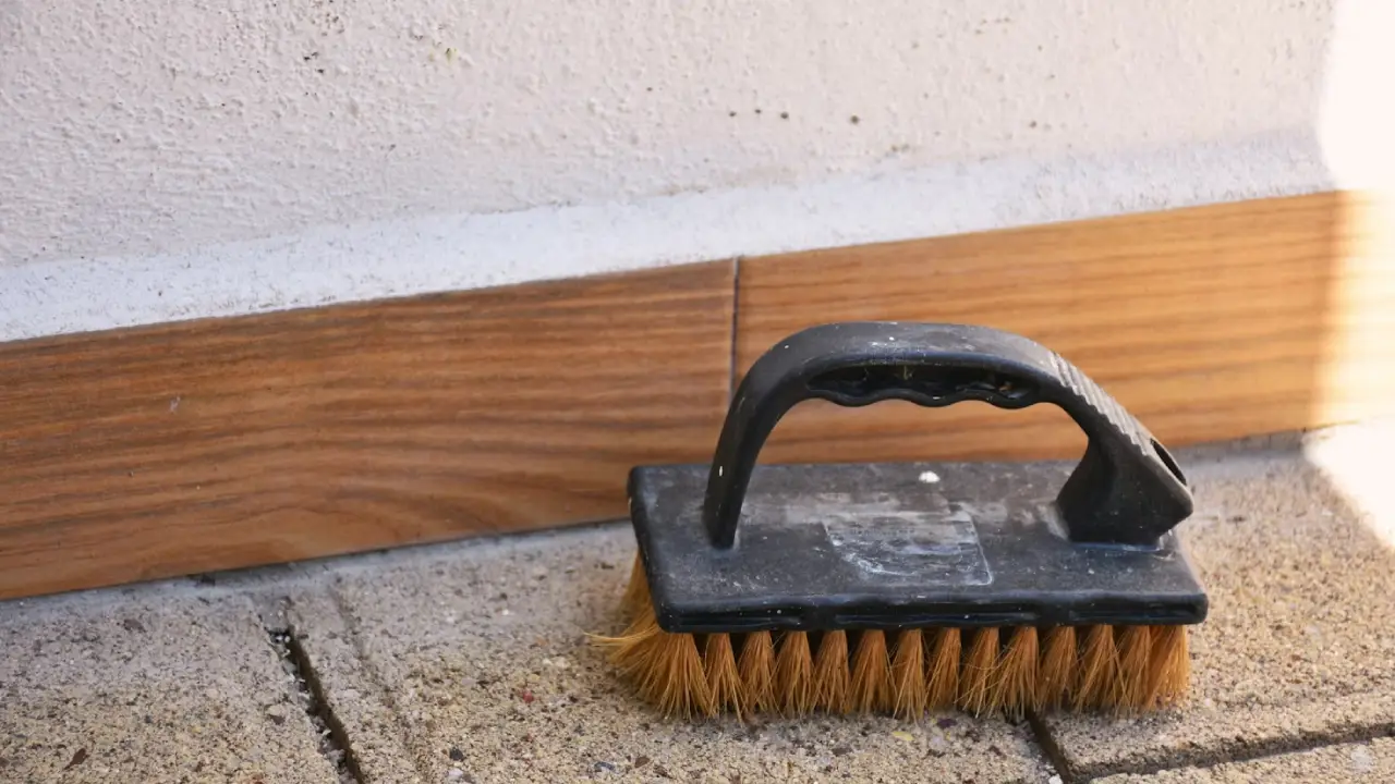 Gros plan sur une brosse posée par terre qui a servi à faire un nettoyage de façade